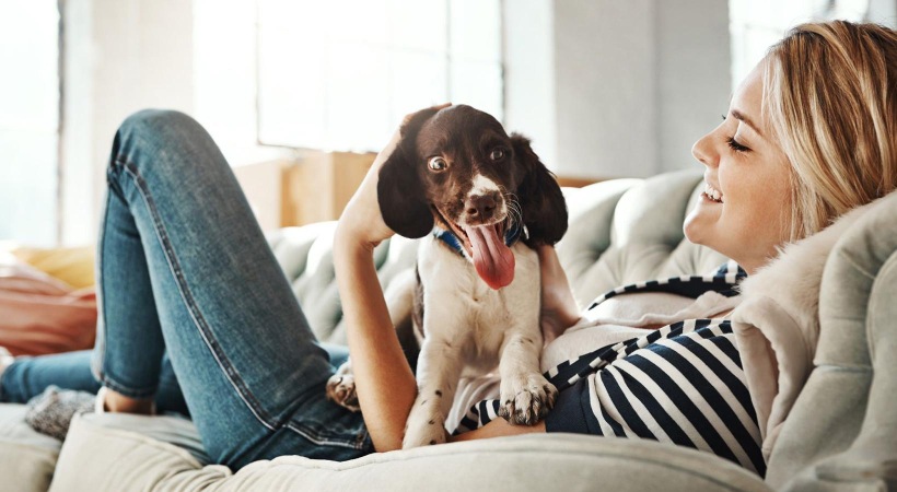 woman lies on a couch and pets her dog